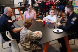 photo of children eating pizza with policemen in the library