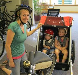 mother in bike helmet with children in carrier.