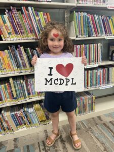 photo of little girl holding a I love my library sign