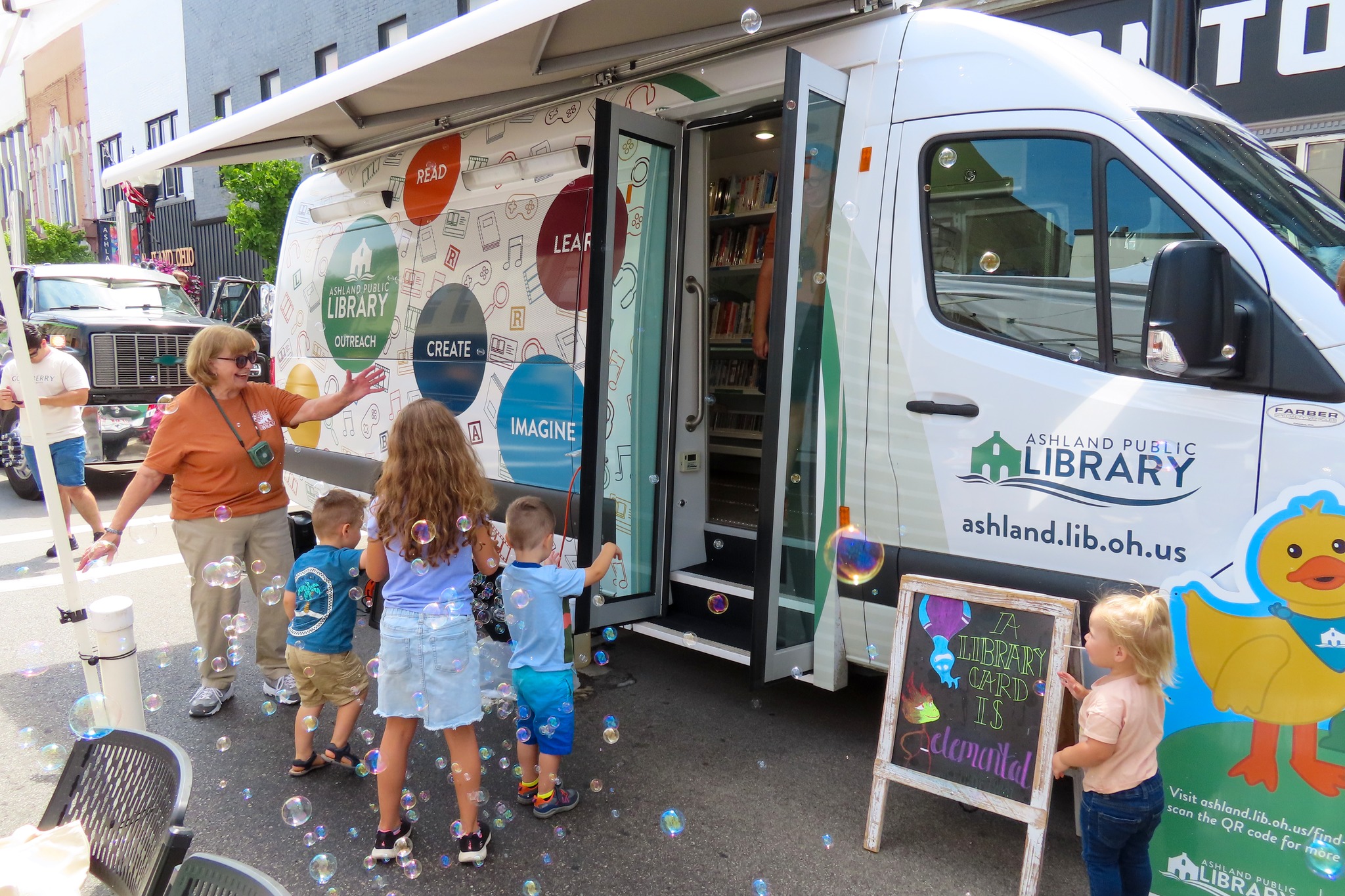 woman and children with bubbles outside outreach van
