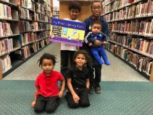 photo of five boys in library with large library card