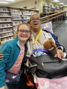 child with an individual in wheelchair inside library