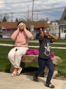 woman and girl looking up at the eclipse outside library