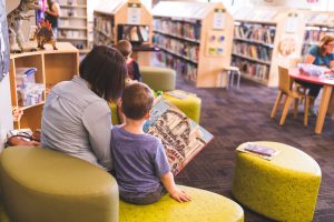 photo of woman and boy reading picture book in library